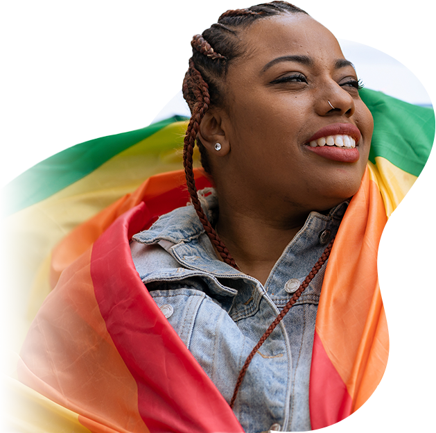 Jovem negra sorridente envolta na bandeira do arco-íris.